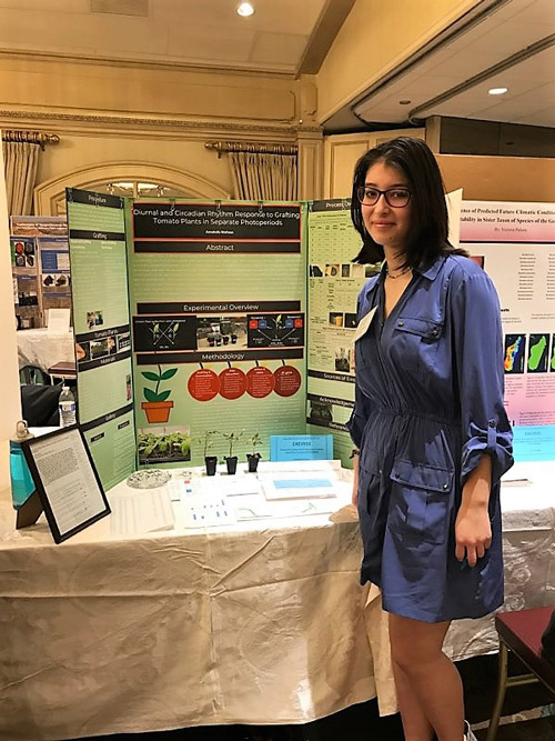 Annabella Matheus stands near a presentation of her highly regarded research.