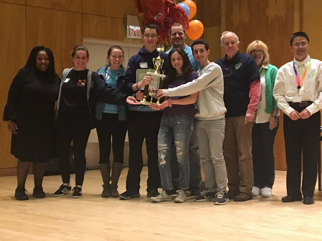 Huntington team members and coaches hold their trophy alongside Ocean Bowl officials.