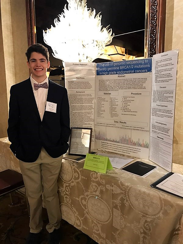 Senior Nolan Piccola stands near his research project presentation board.