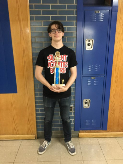 Foster Sullivan holds his second place trophy in the high school hallway.