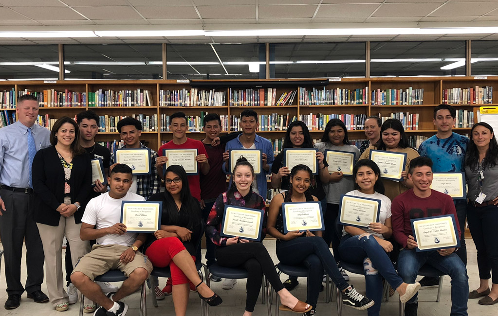The program participants show off their certificates in the high school library.