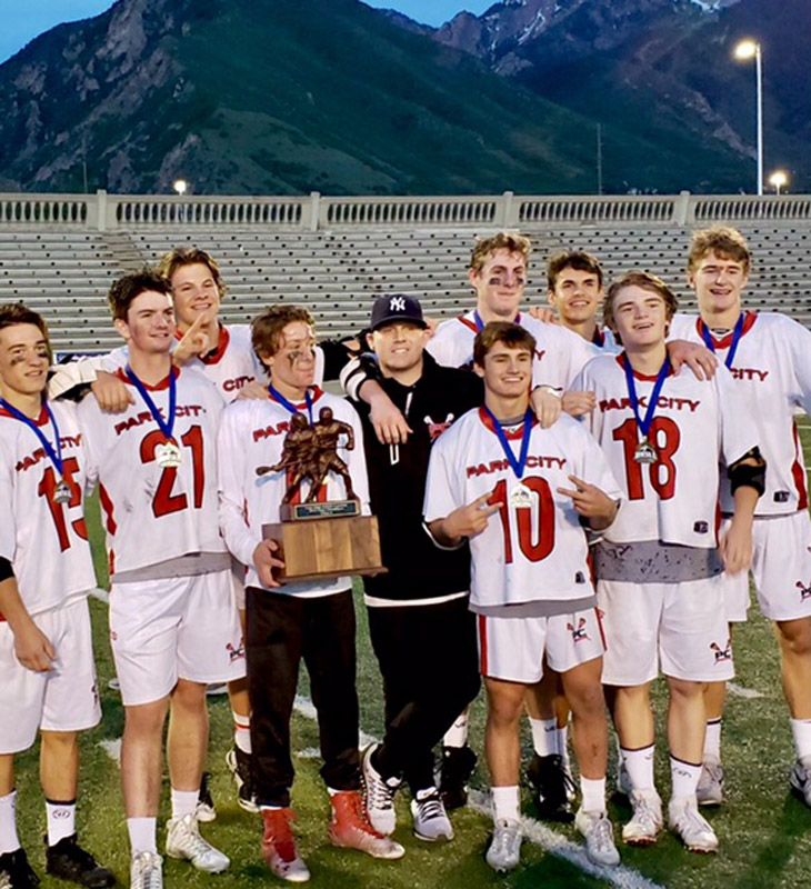 Brian Bilzi wears a NY Yankees hat as he poses with the Park City, Utah lacrosse team that just won the state title.