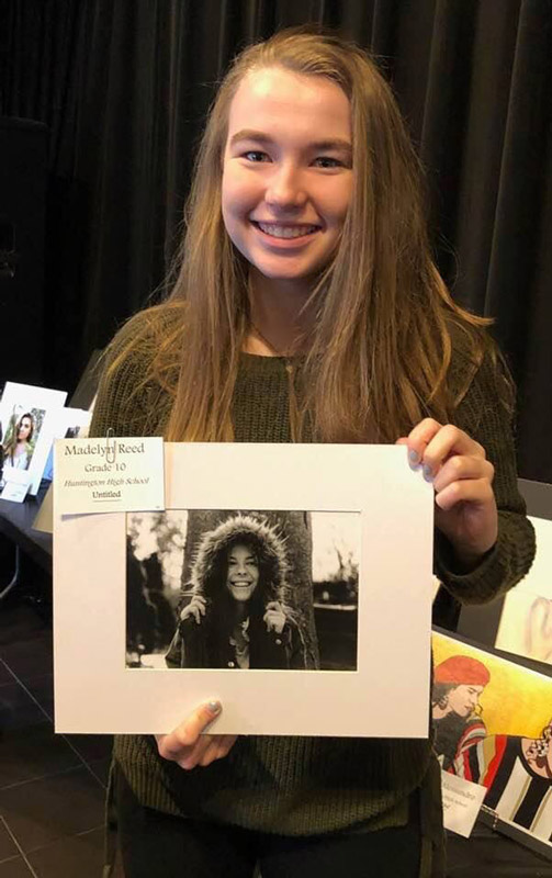 Huntington sophomore Maddie Reed holds one of her photographs on exhibit.
