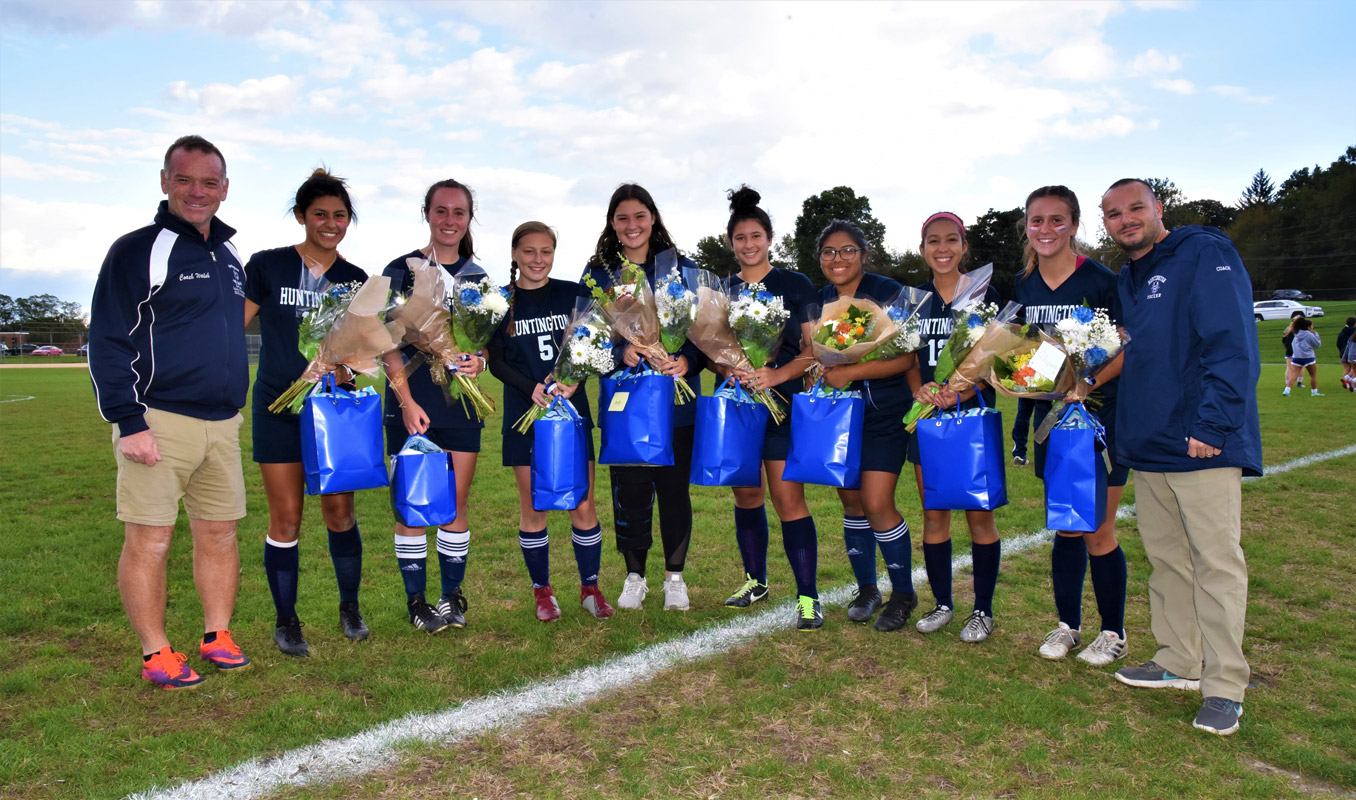 Huntington girls' soccer's eight seniors are flanked by coaches John Walsh and Vincent Tannazzo.