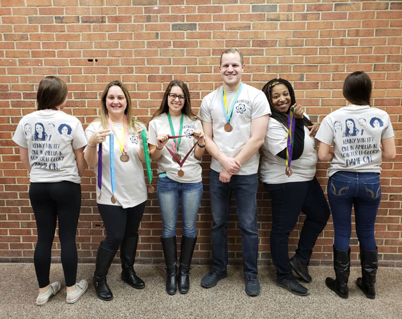 Huntington Science Olympiad faculty coaches are flanked by two team members showing off special t-shirts.