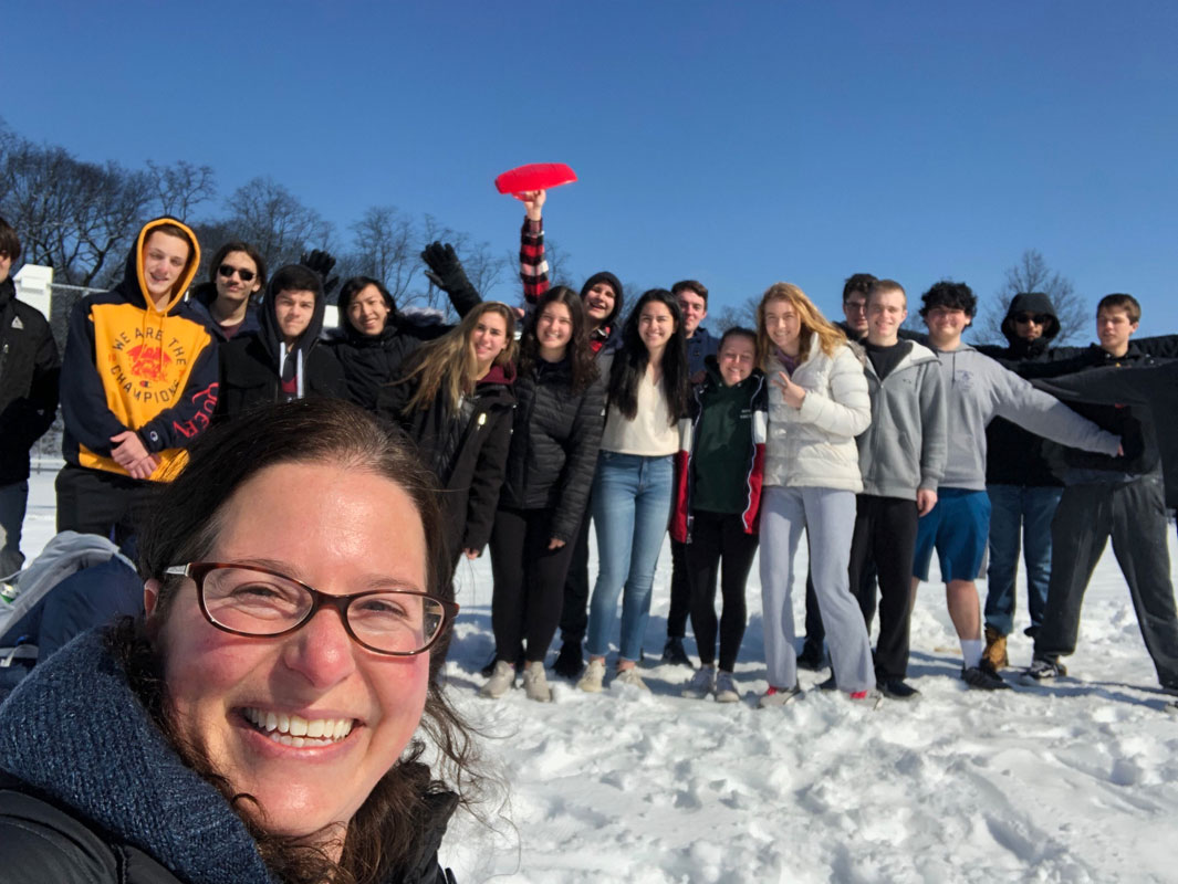 AP Physics teacher Stacey Byrnes with a class of happy students in the background.