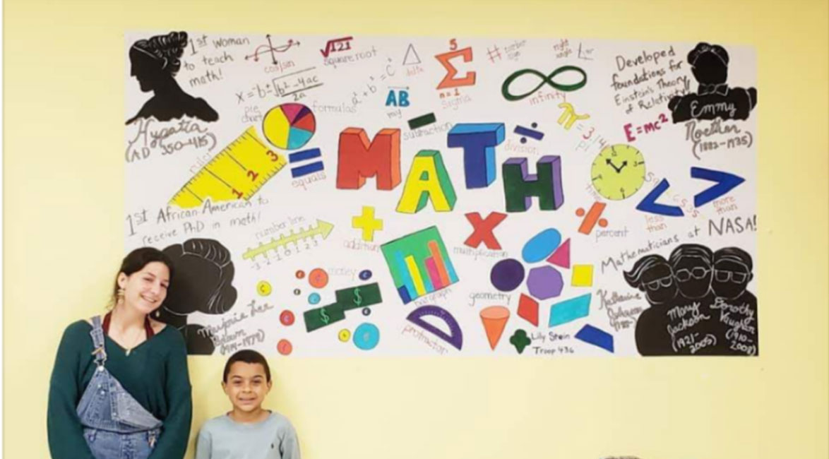 Lily Stein stands near her mural at Tri-CYA with one of the organization's after school program participants.
