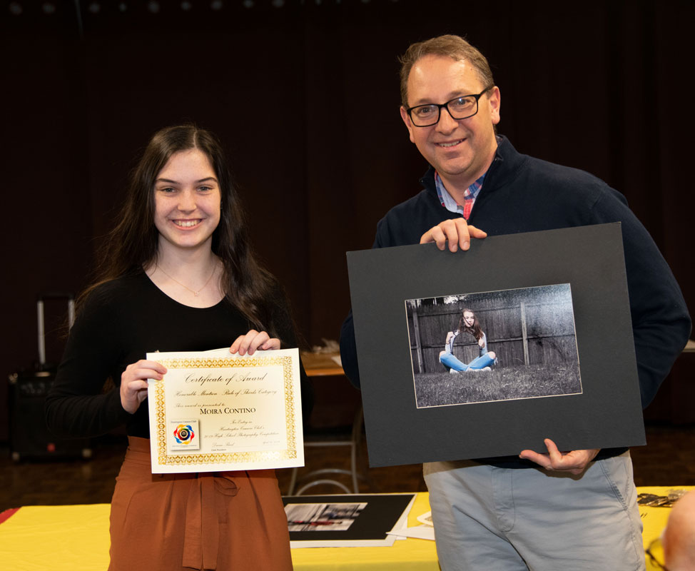 Moria Contino with Huntington Camera Club President Darin Reed as he holds her award winning photo.