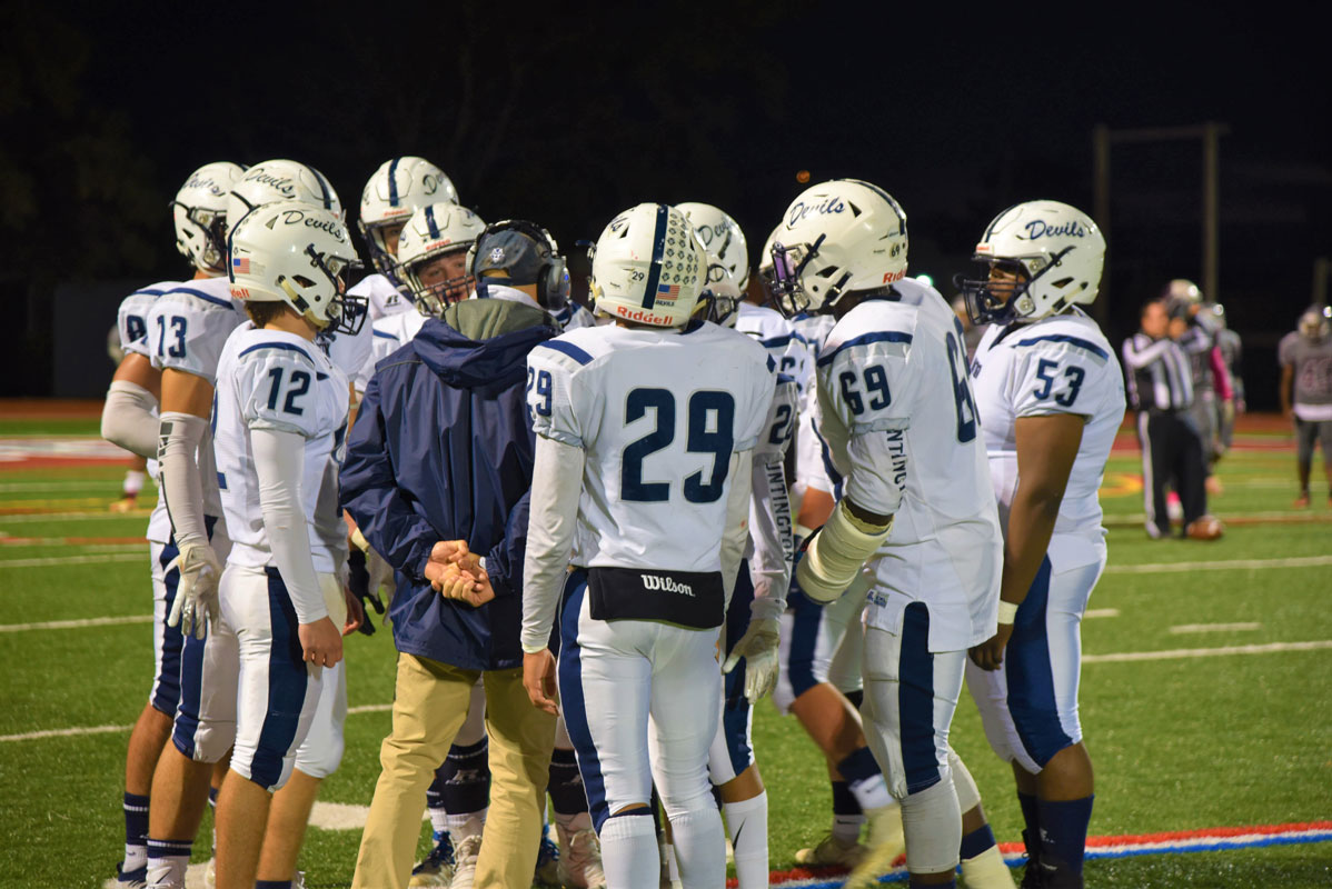 Huntington's offensive unit gathers around head coach Steve Muller during a timeout last Friday in Deer Park.