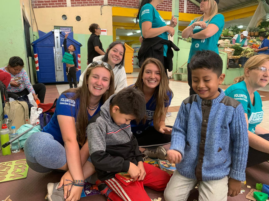 Peyton Kalb and Abby Maichin volunteering with children in a market in Quito, Ecuador.