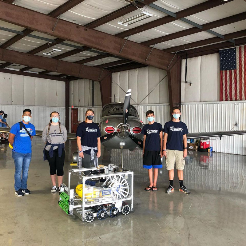 Huntington Robotics team members with their robot, Smokey in a LI MacArthur Airport hangar.