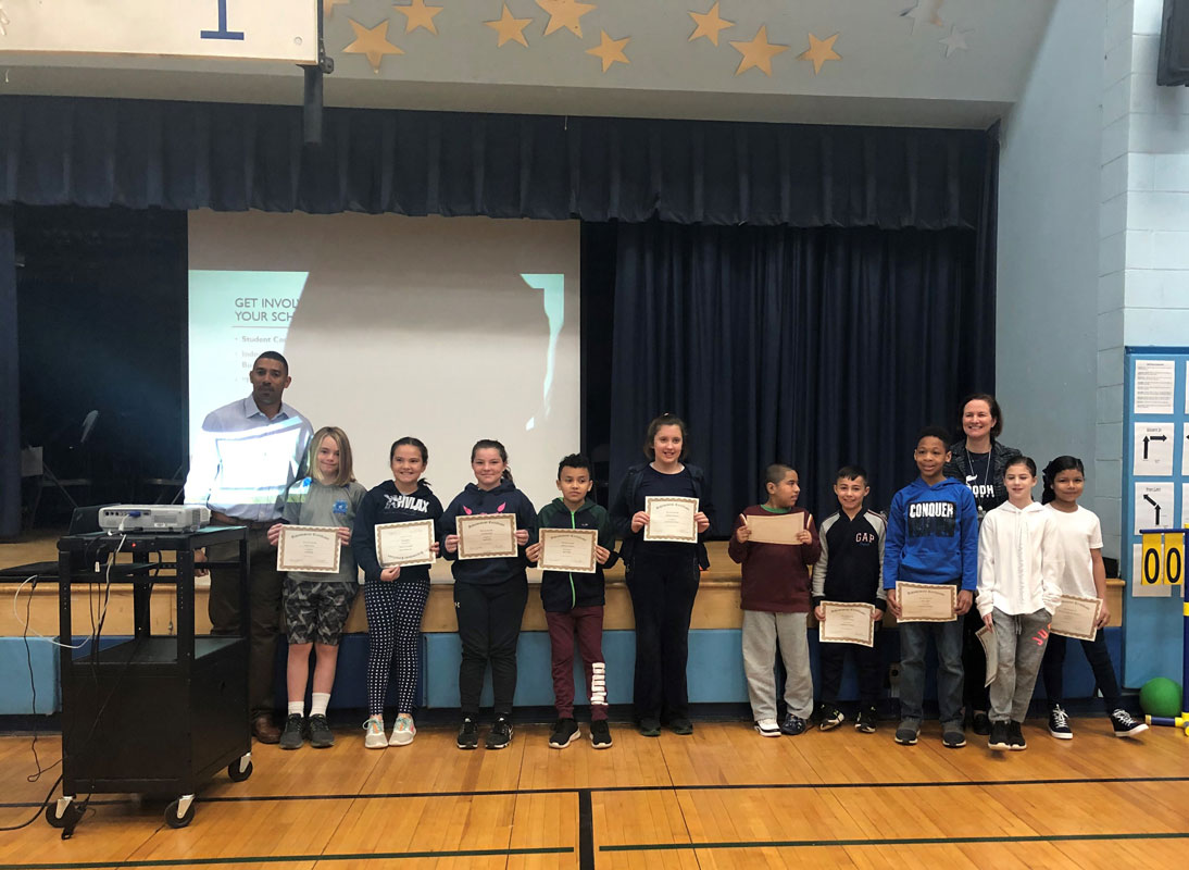 Principal Lara Gonzalez and Dean Julian Watts with award recipients at a town hall meeting.