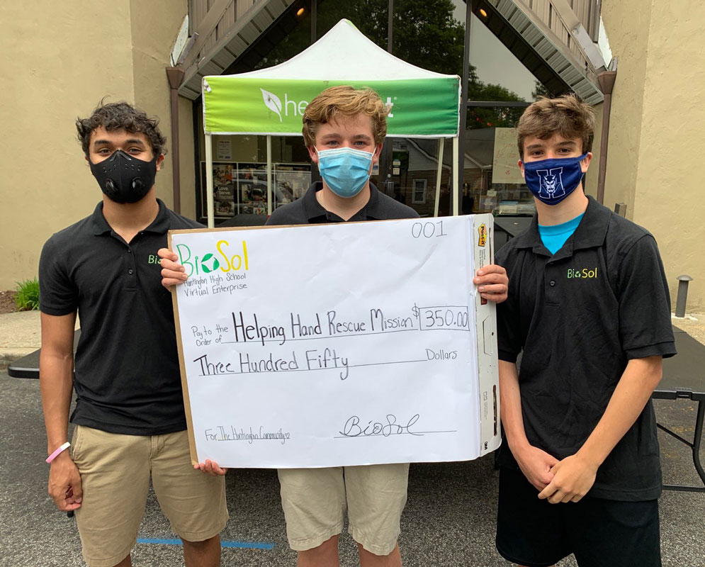John Holly (center) holds a mock check while flanked by Isaiah James and Marcus Maerz.