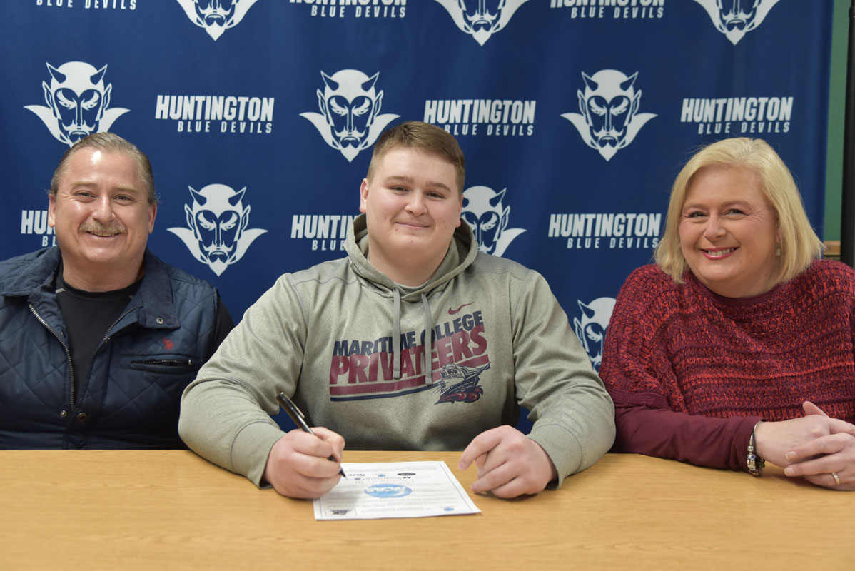 Flanked by his parents, Huntington senior Aidan Mrotzek has committed to play football at SUNY Maritime College 