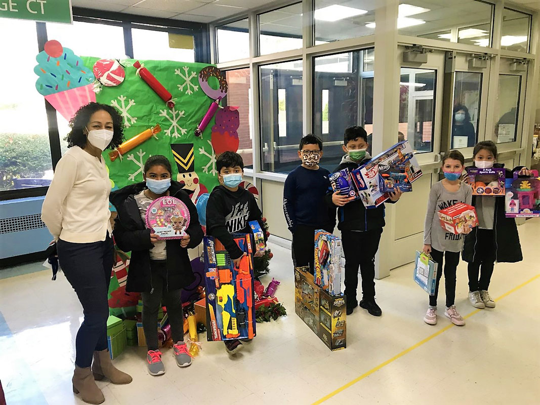 Social worker Gisselle Soto with third graders showing off donated toys.