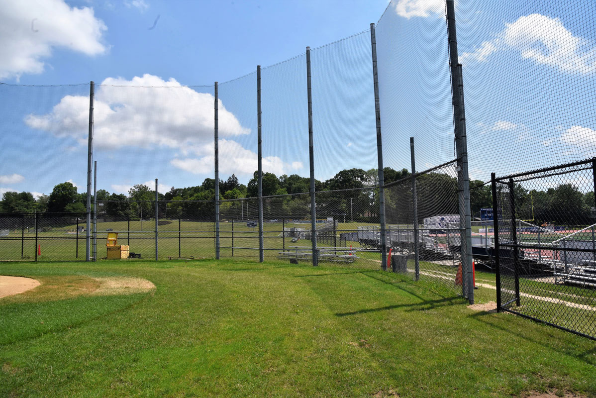 The top of the backstop has been removed so that the catcher can make a play of a popup in foul territory 