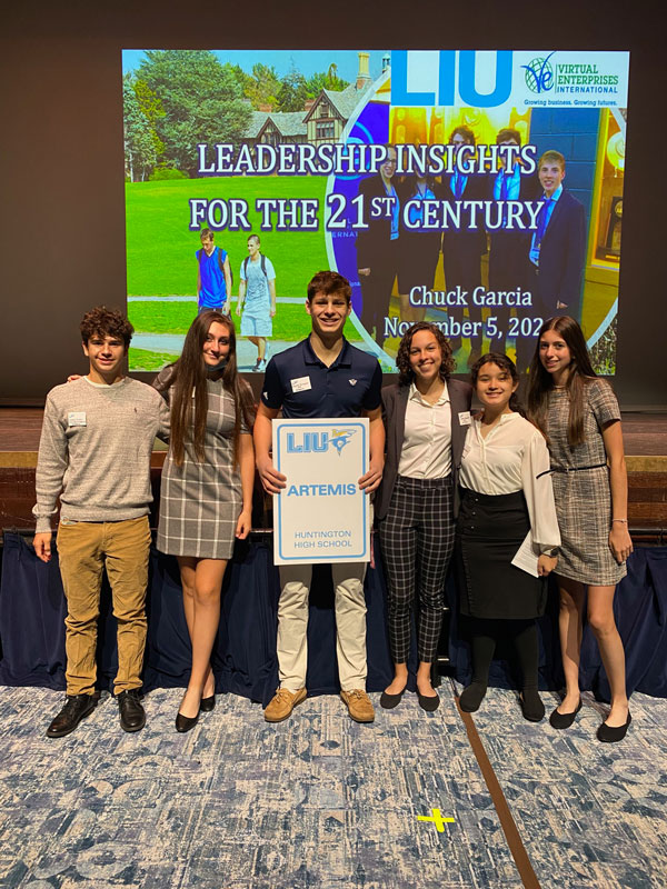 Charlie Girimonti holds the Artemis corporate sign at LIU Post's Virtual Enterprise leadership conference.