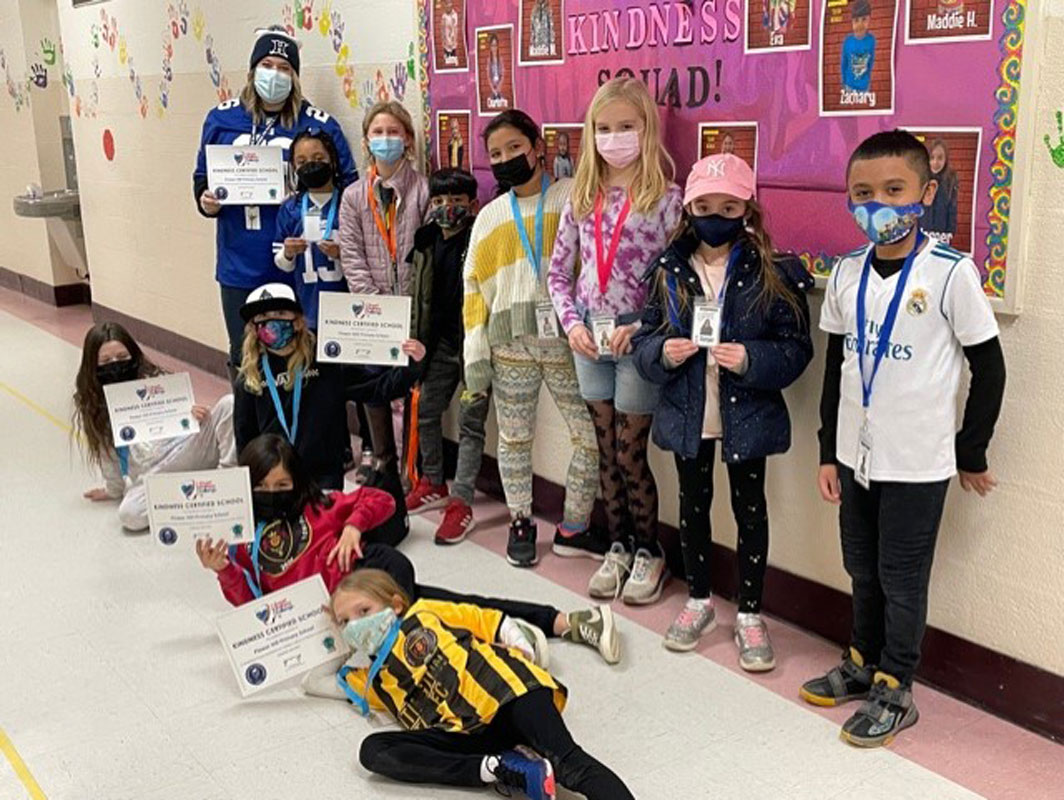 Flower Hill students show-off kindness certificates in front of a kindness bulletin board