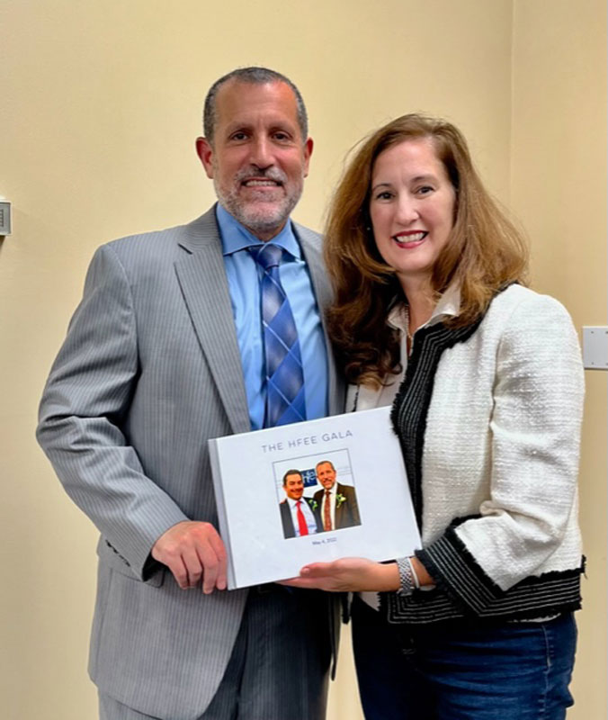 2022 honoree Jim Polansky and HFEE President Jennifer Stevens hold a memento book from last year's gala.