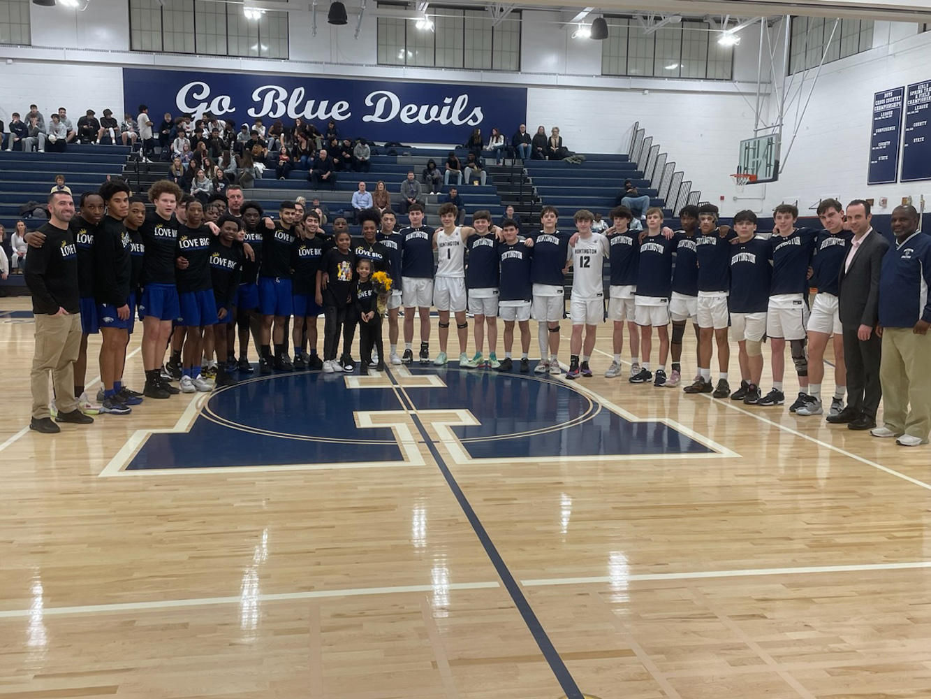  The Copiague and Huntington basketball teams surround Carmyne Payton's mom, Tiffany Wofford last Friday night   